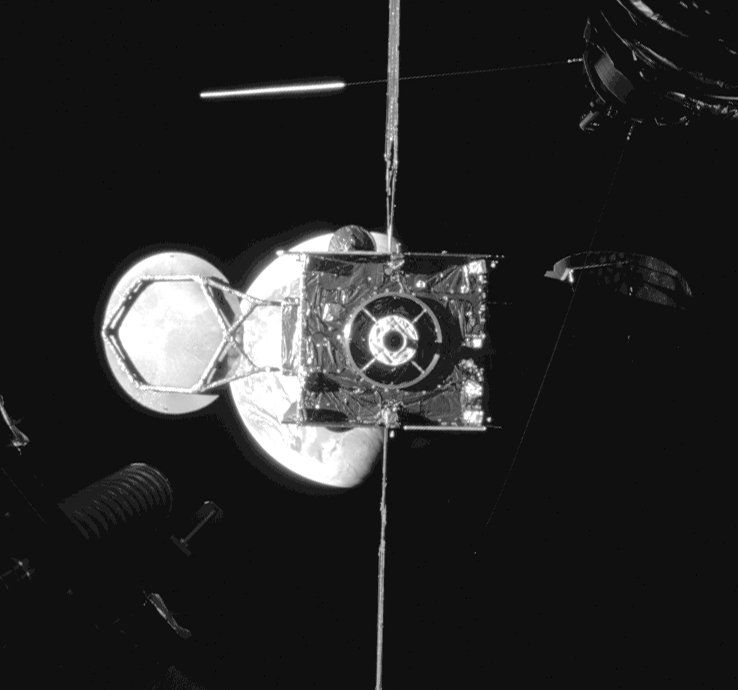 Intelsat 901 photographié depuis MEV-1 au moment de la séparation, la Terre en arrière-plan, des éléments du remorqueur visibles aux angles de l'image